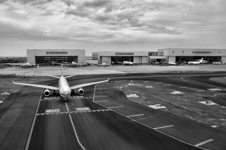 gray scale of air plane on runway under cloudy day